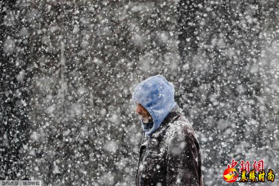 资料图：弗吉尼亚的天气预报中心预测，当地在20日会有几英尺的降雪，之后将会伴随雨夹雪和霜冻。图为行人走在暴风雪肆掠的费城街头。